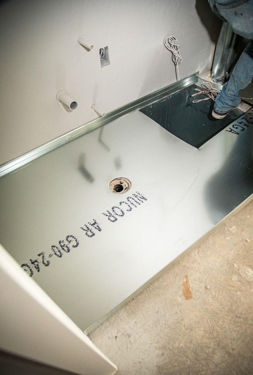 Woman in straw hat smiles, holding wine glass near a lake.