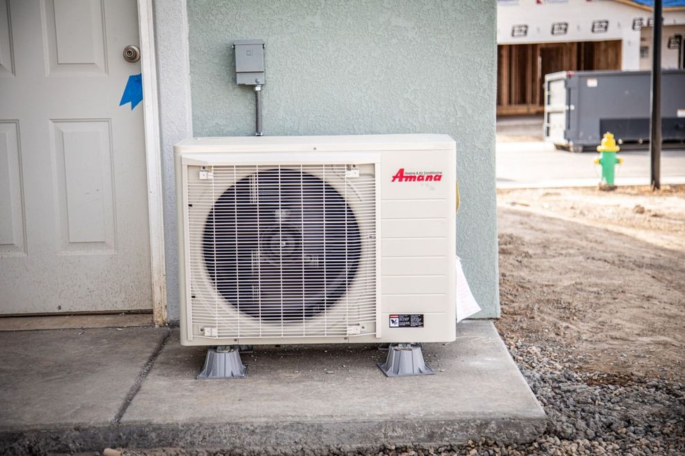 Exterior air conditioning unit on a concrete pad next to a door. Construction site setting.