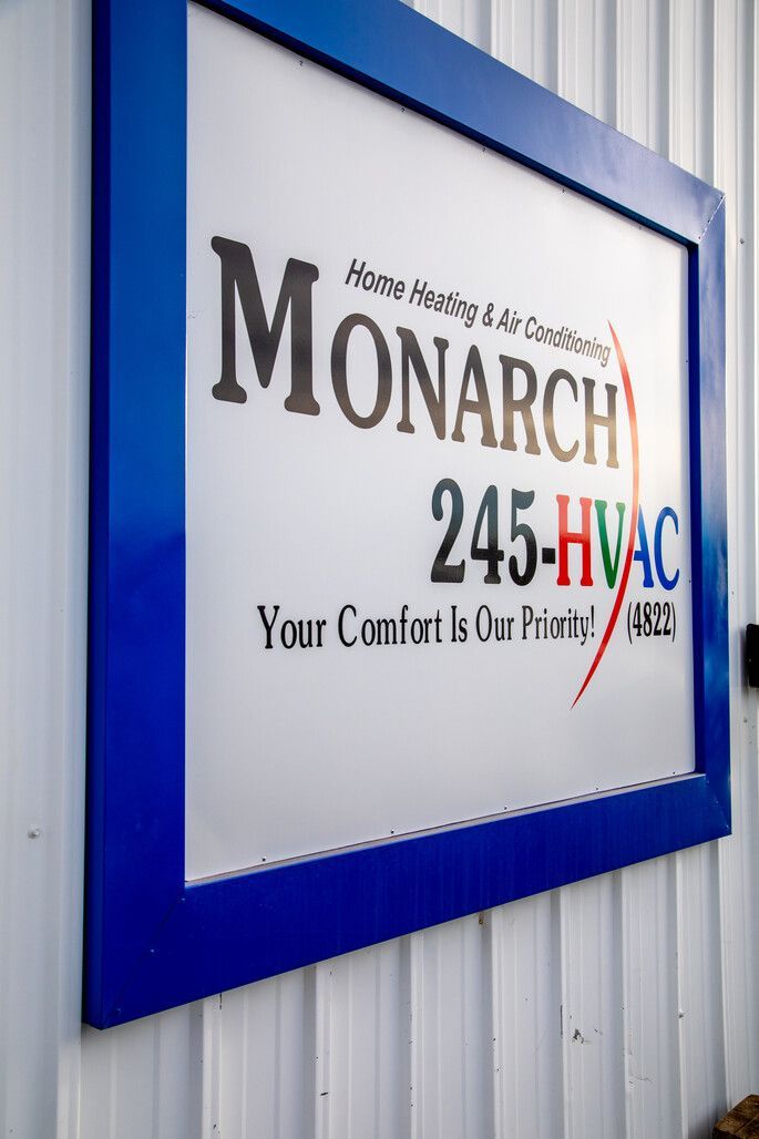 Woman in straw hat smiles, holding wine glass near a lake.