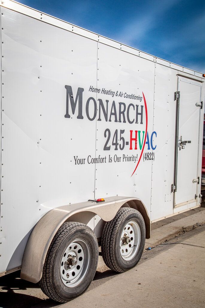 Woman in straw hat smiles, holding wine glass near a lake.