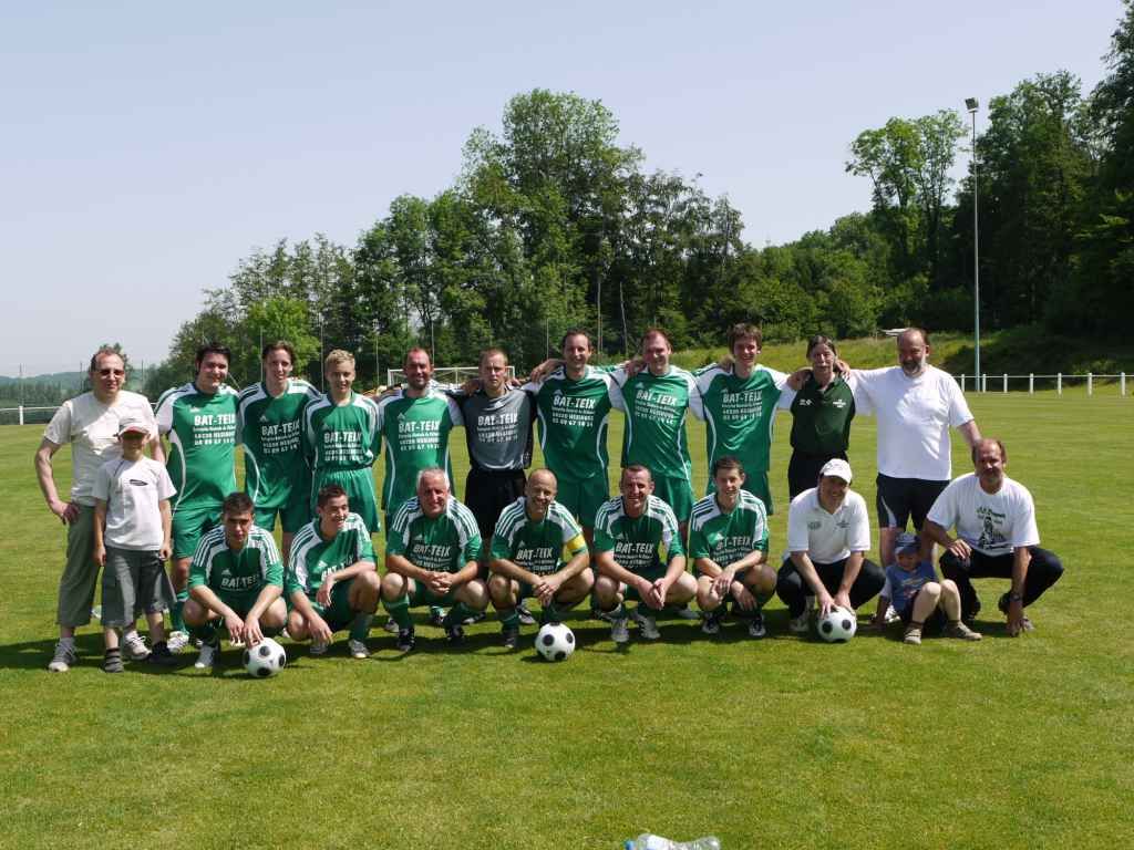 Un groupe de personnes posant pour une photo avec des ballons de football sur un terrain