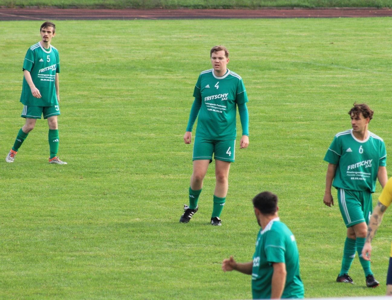 Un groupe de joueurs de football en uniformes verts sont assis par terre