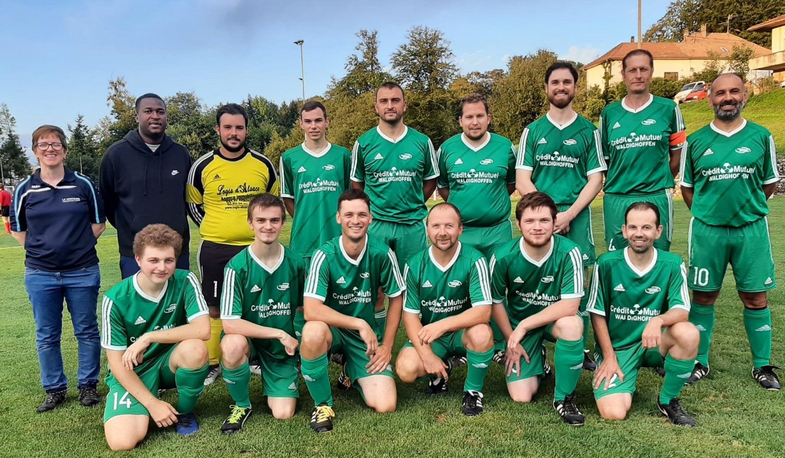 Une équipe de football pose pour une photo sur un terrain.