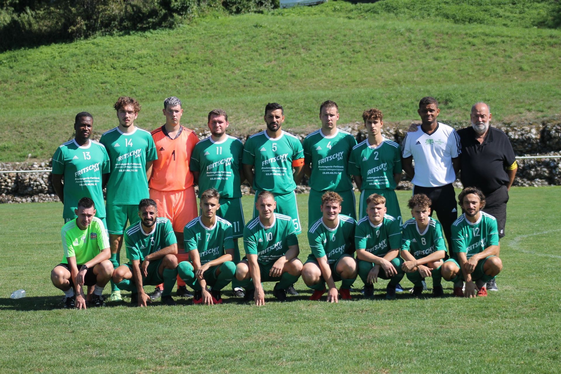 Un groupe de joueurs de football pose pour une photo sur un terrain.