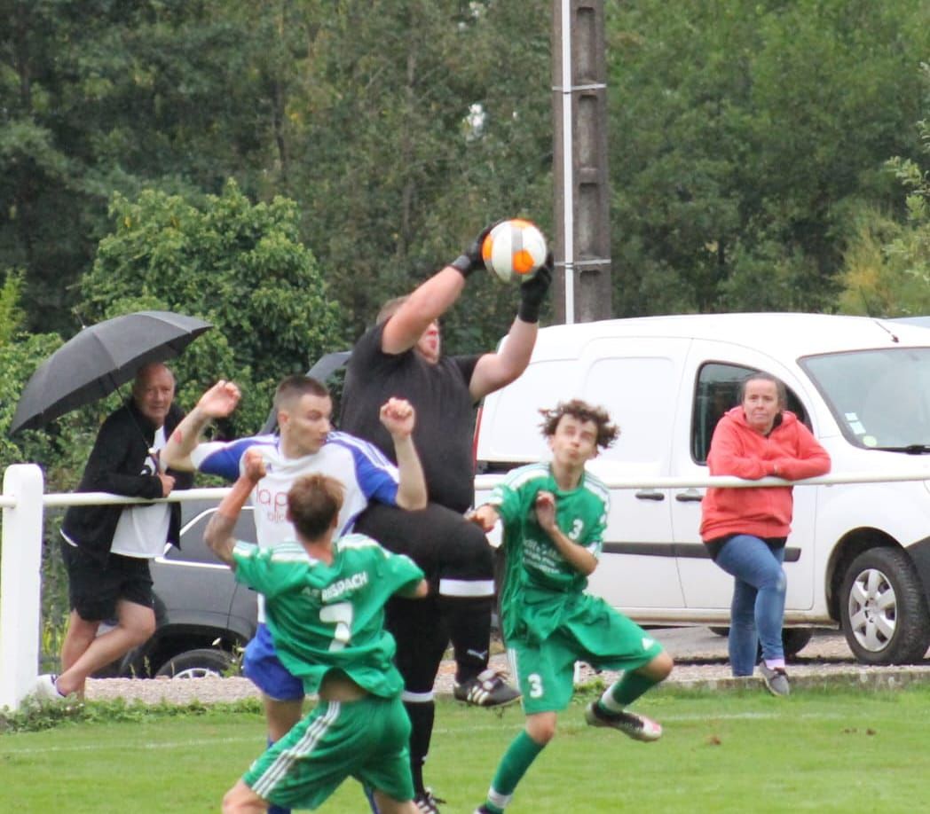 Un groupe de joueurs de football jouent sur un terrain avec une camionnette blanche en arrière-plan