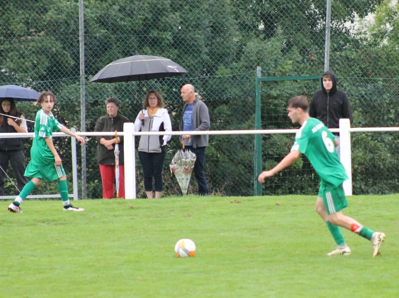 Un groupe de personnes regarde un match de football sur un terrain.