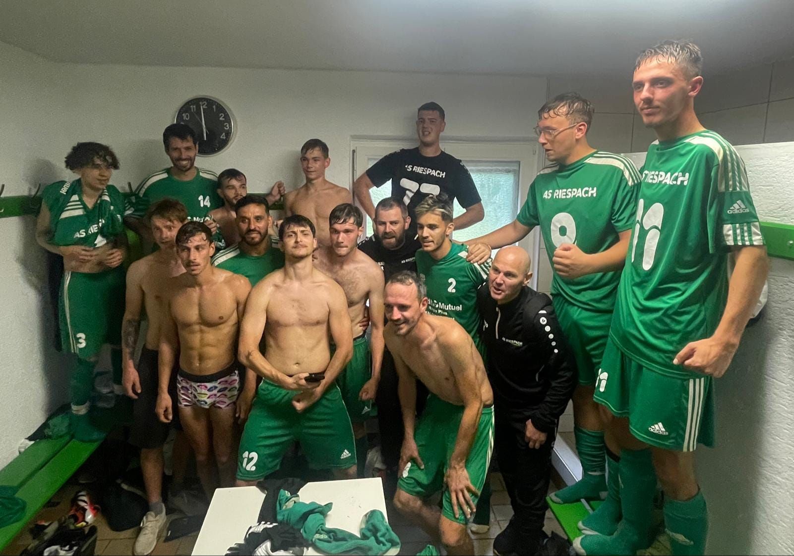 Un groupe de joueurs de football posant pour une photo dans un vestiaire.