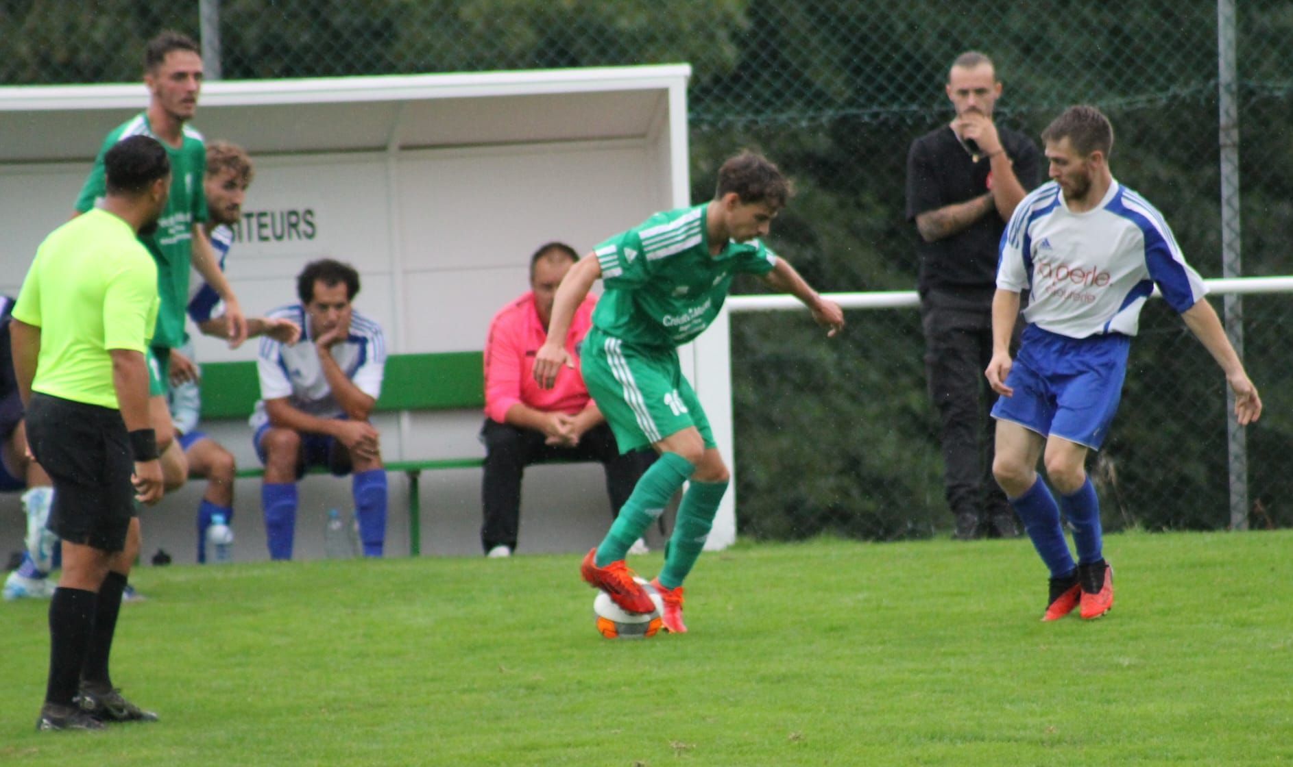 Un groupe d'hommes jouent au football sur un terrain.