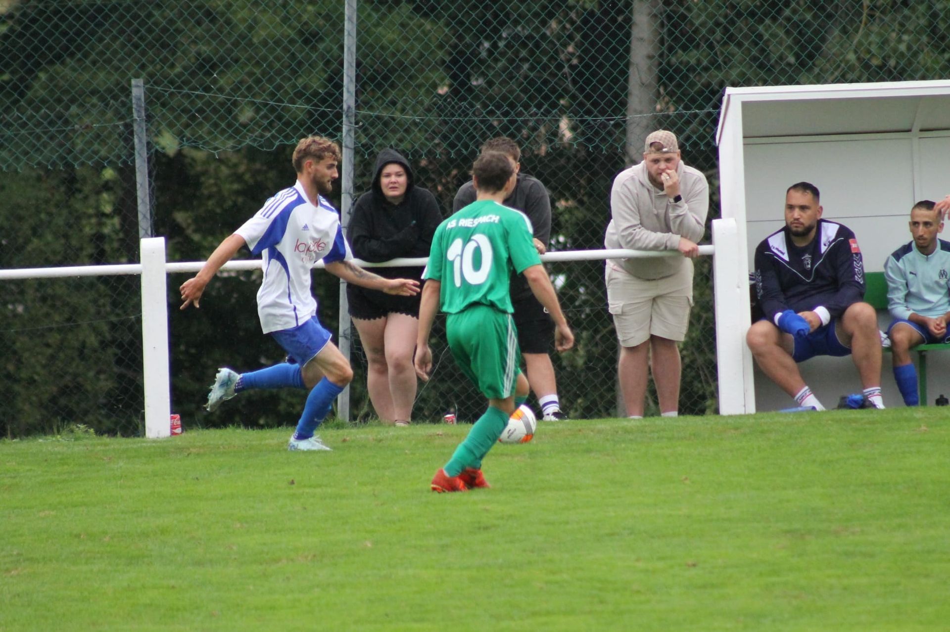 Un homme portant un maillot vert avec le numéro 10 dessus frappe un ballon de football sur un terrain.