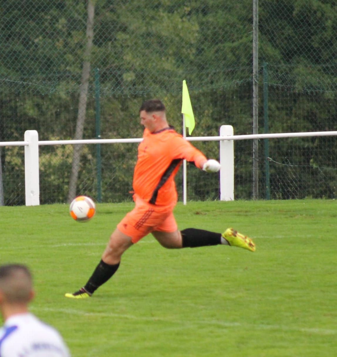 Un homme en short orange frappe un ballon de football