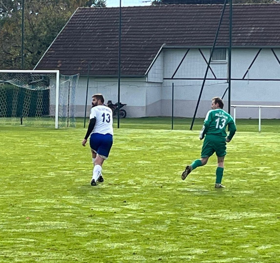 Deux hommes jouent au football sur un terrain et l'un d'eux porte le numéro 13 sur son maillot