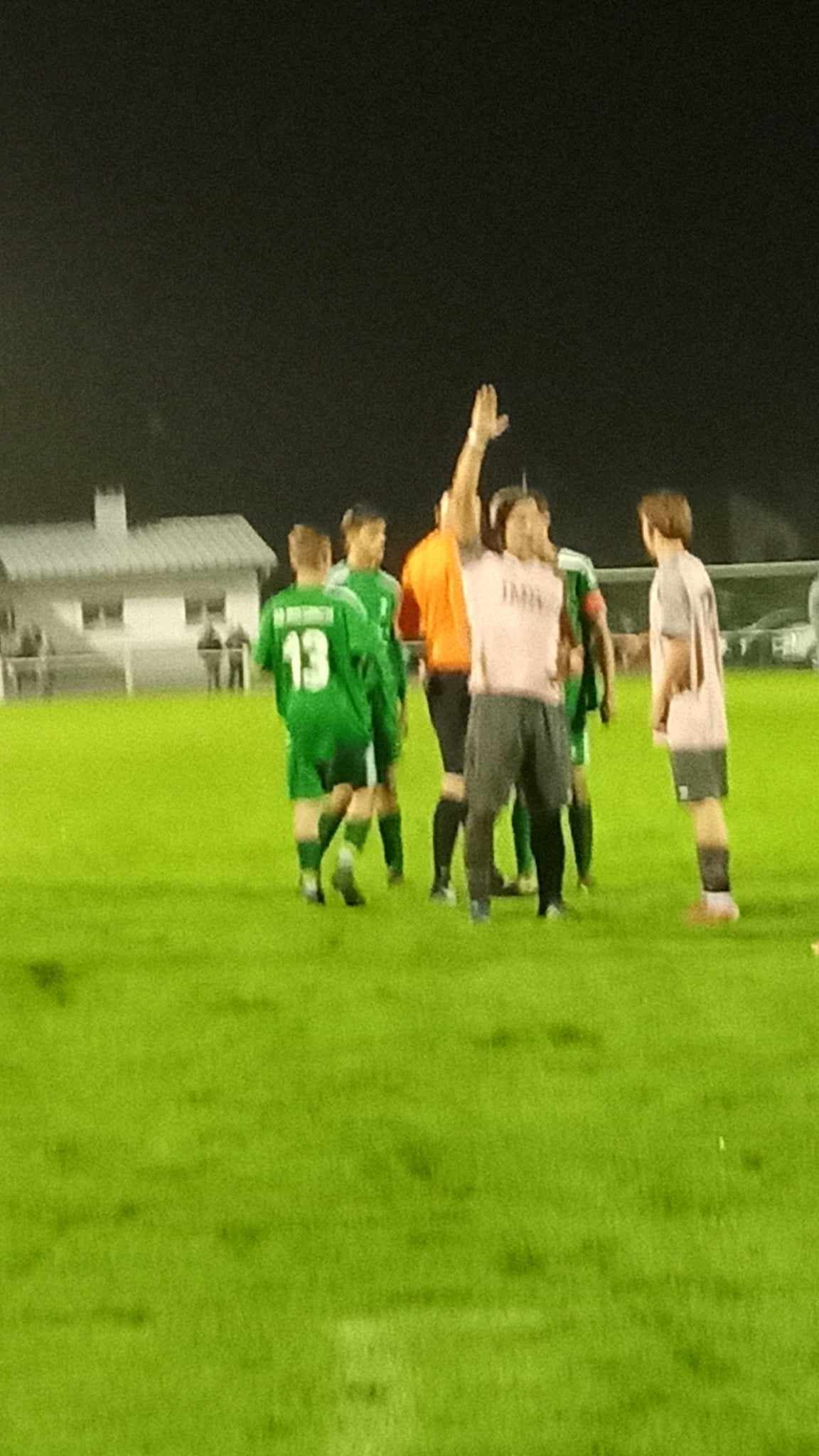 Un groupe de personnes joue au football sur un terrain la nuit.