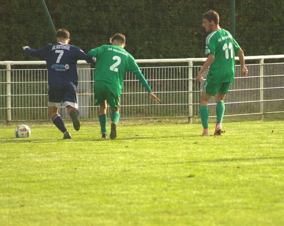 Un groupe de footballeurs jouent au football sur un terrain.