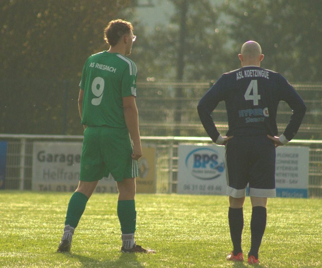 Deux joueurs de football sont debout sur un terrain et l'un d'eux porte le numéro 4 sur le dos