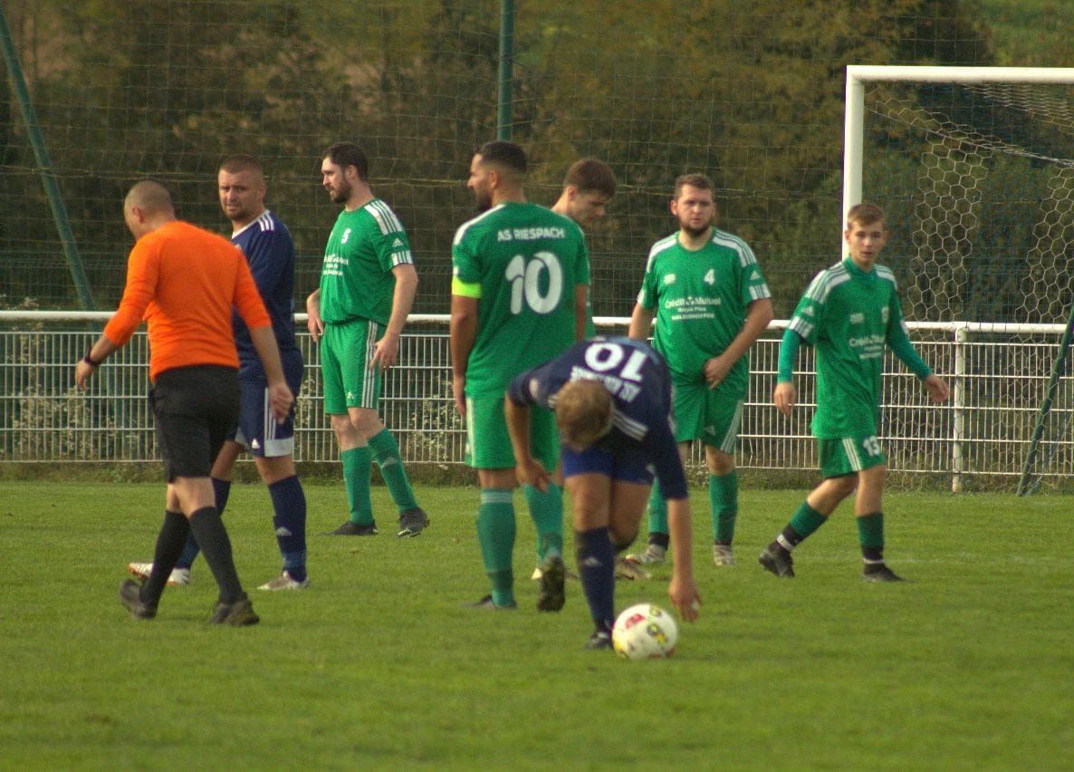 Un groupe de joueurs de football jouent à un jeu sur un terrain.