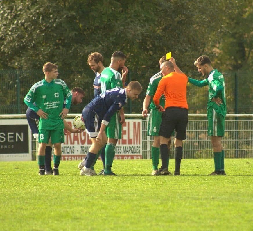 Un groupe de joueurs de football sur un terrain avec un panneau en arrière-plan indiquant sen
