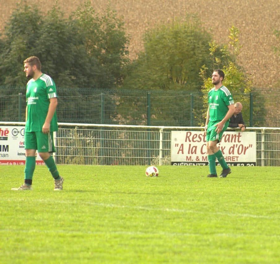 Deux joueurs de football sur un terrain avec un panneau de restaurant en arrière-plan