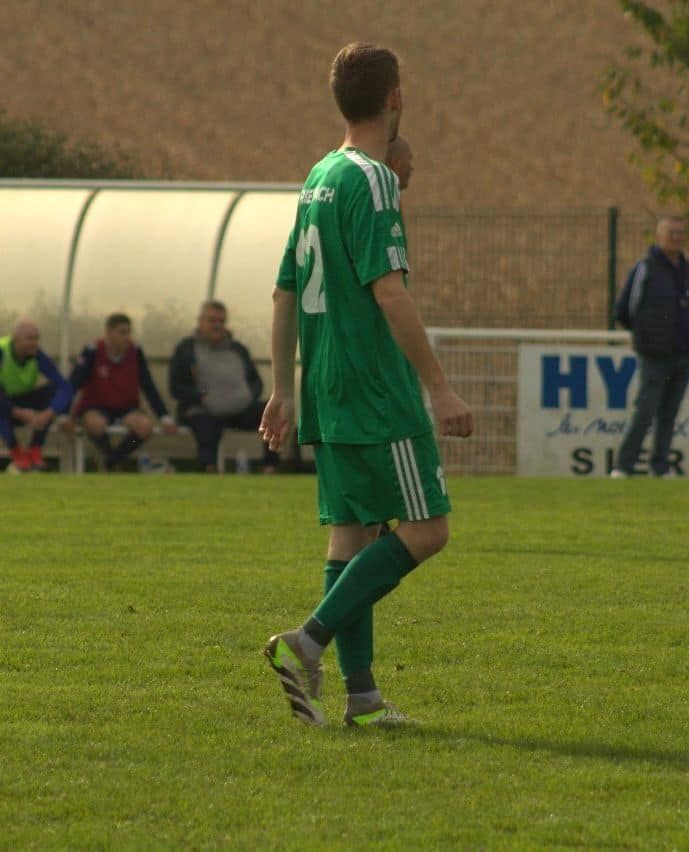 Un joueur de football portant un maillot vert avec le numéro 2 dessus