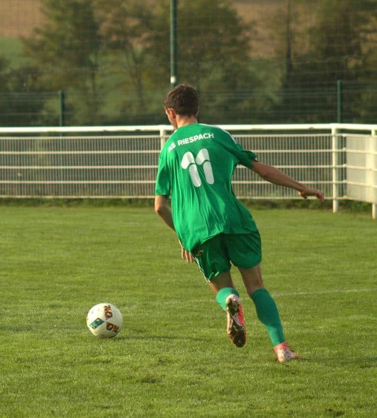 Un joueur de football avec le numéro 11 sur le dos frappe un ballon de football