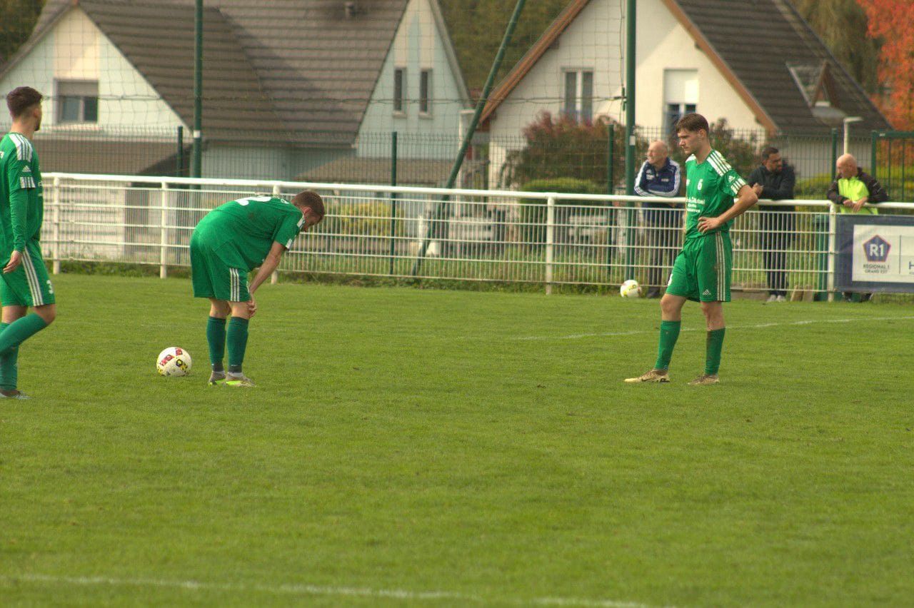 Un groupe de footballeurs jouent au football sur un terrain.