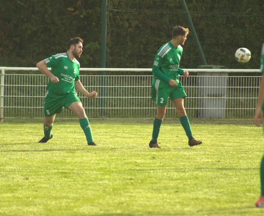 Un groupe de footballeurs jouent au football sur un terrain.