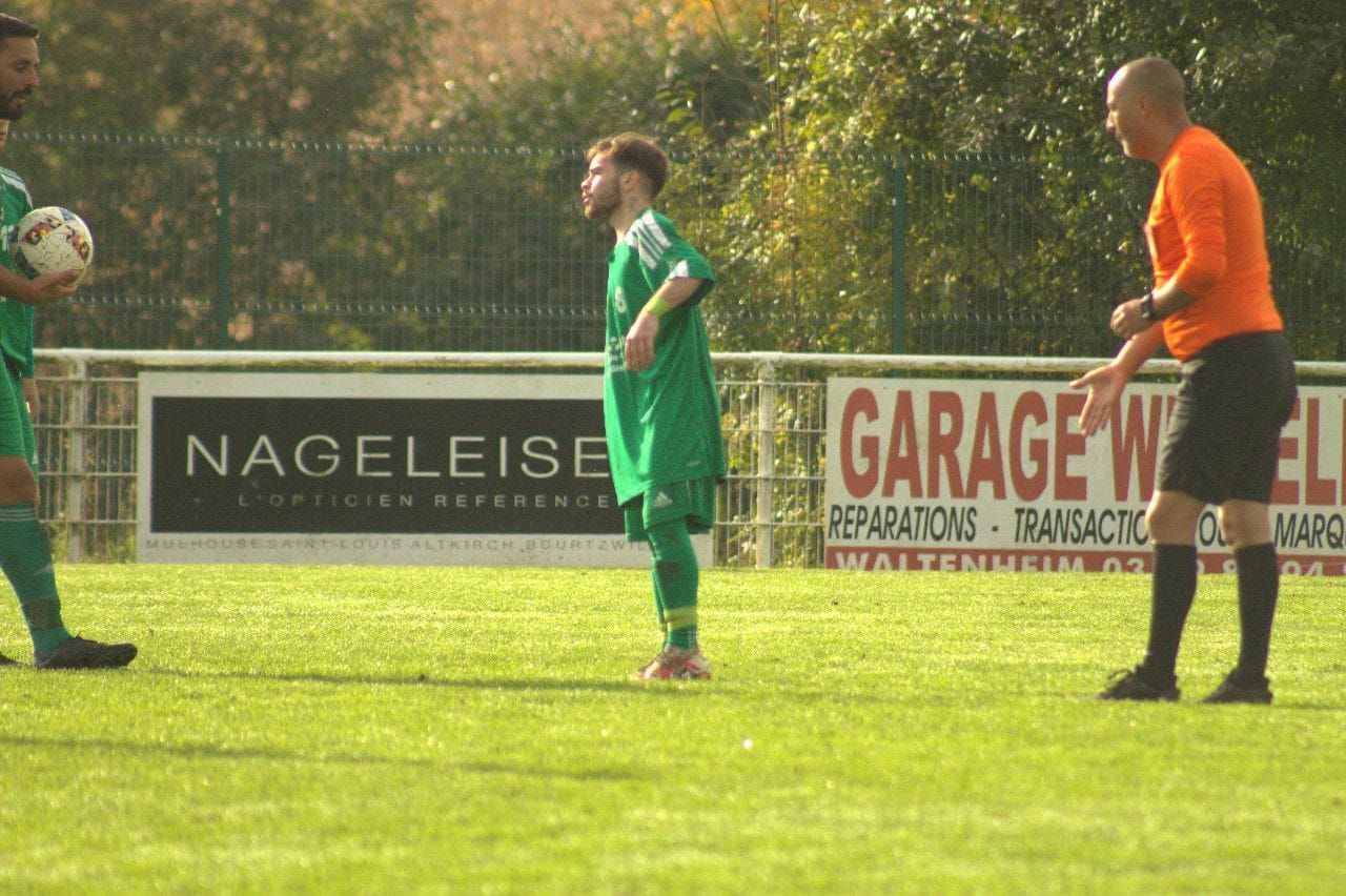 Un groupe de footballeurs jouent sur un terrain devant un panneau de garage.