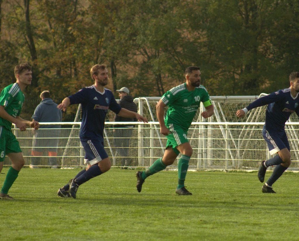 Un groupe de joueurs de football courent sur un terrain