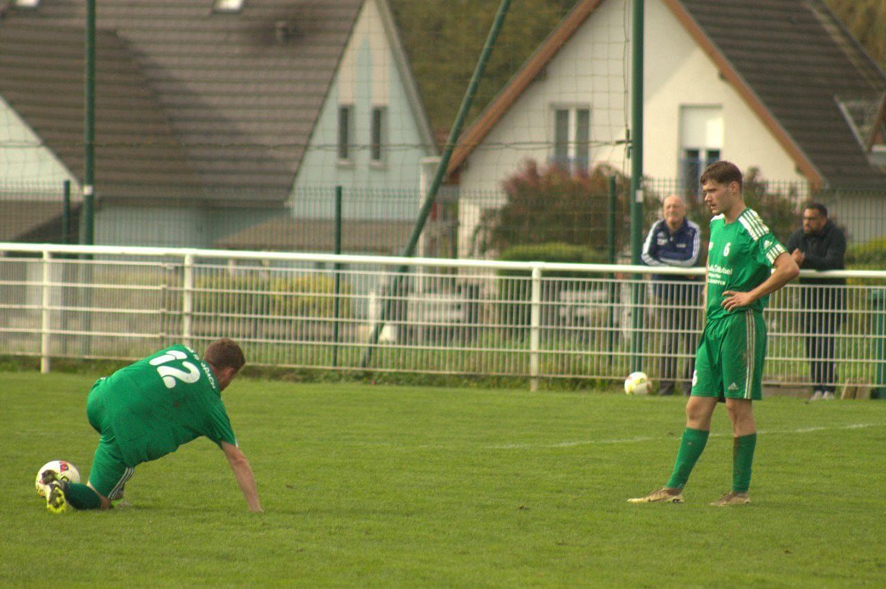Un joueur de football avec le numéro 22 sur son maillot est à genoux sur le terrain.