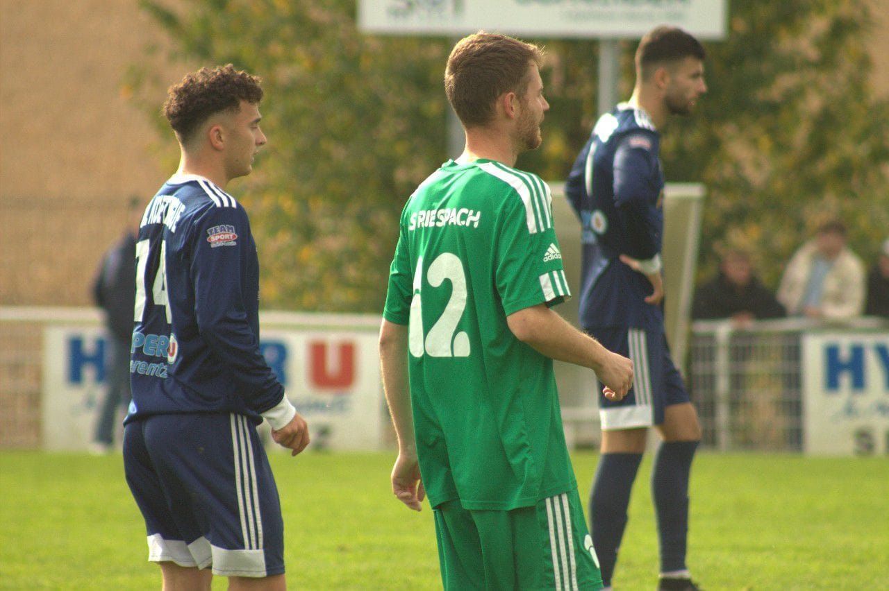 Un groupe de joueurs de football se tiennent sur un terrain et discutent entre eux.