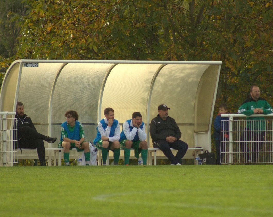 Un groupe de joueurs de football assis dans un abri sur un terrain