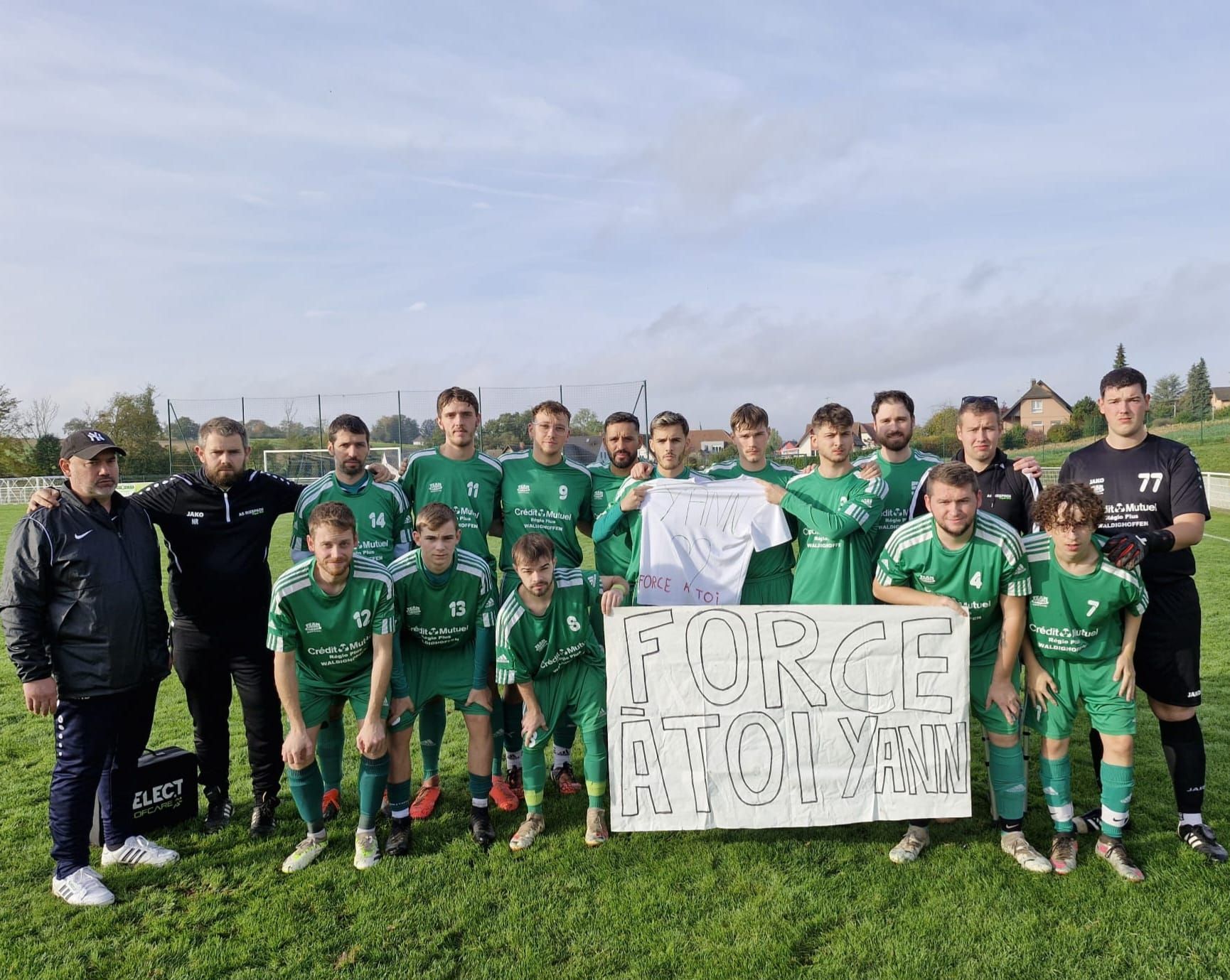 Une équipe de football pose pour une photo sur un terrain.