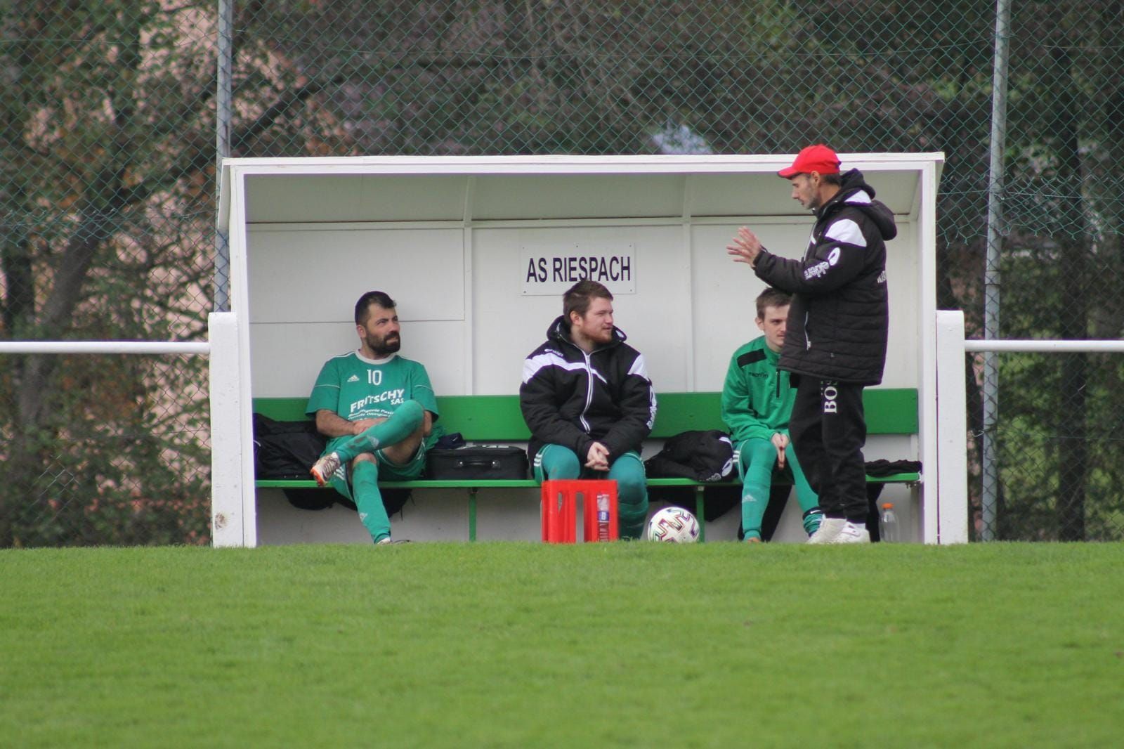 Un groupe d'hommes sont assis sur un banc sur un terrain de football.