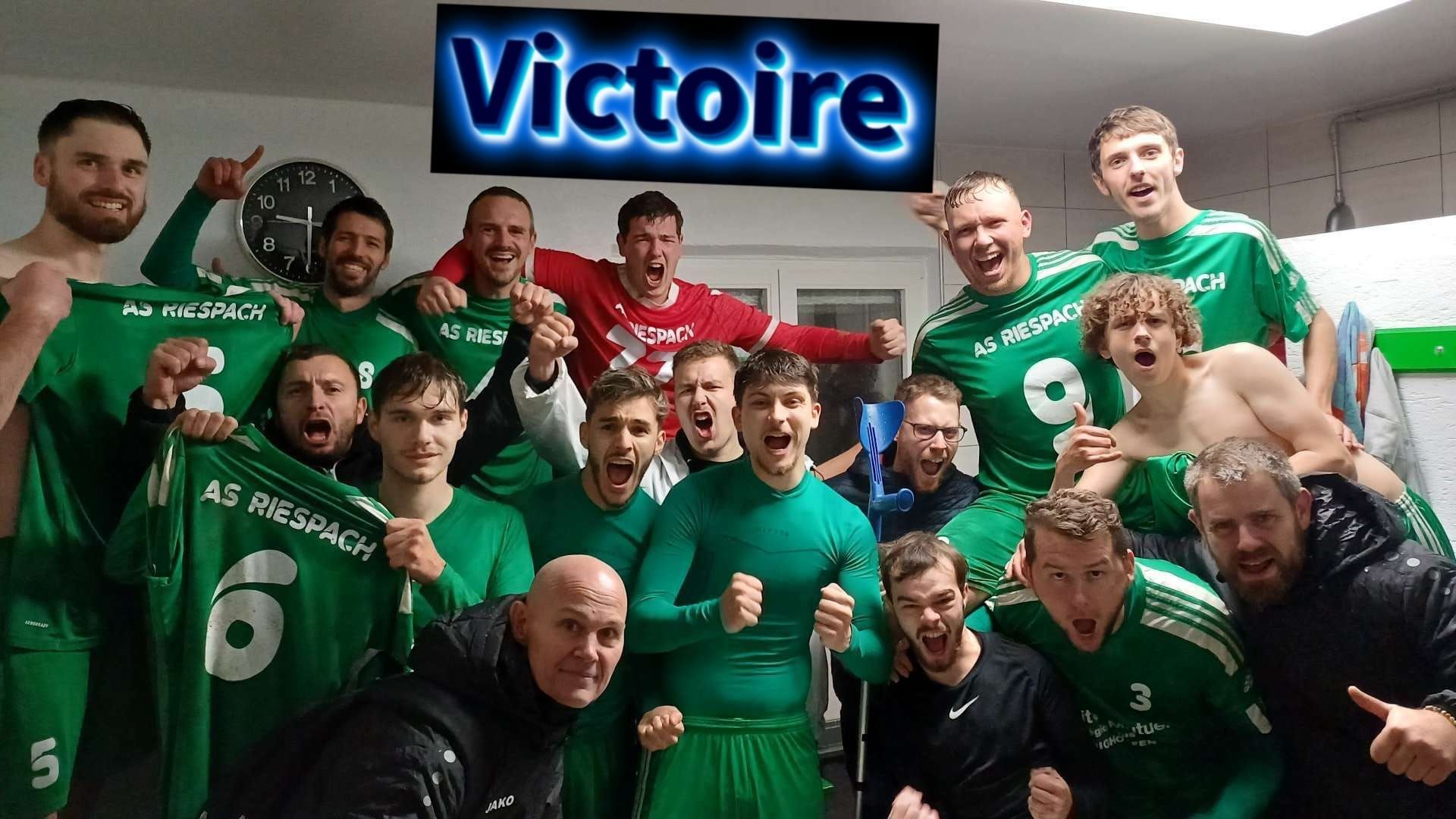 Un groupe d'hommes en chemises vertes posent pour une photo sous un panneau indiquant victoire