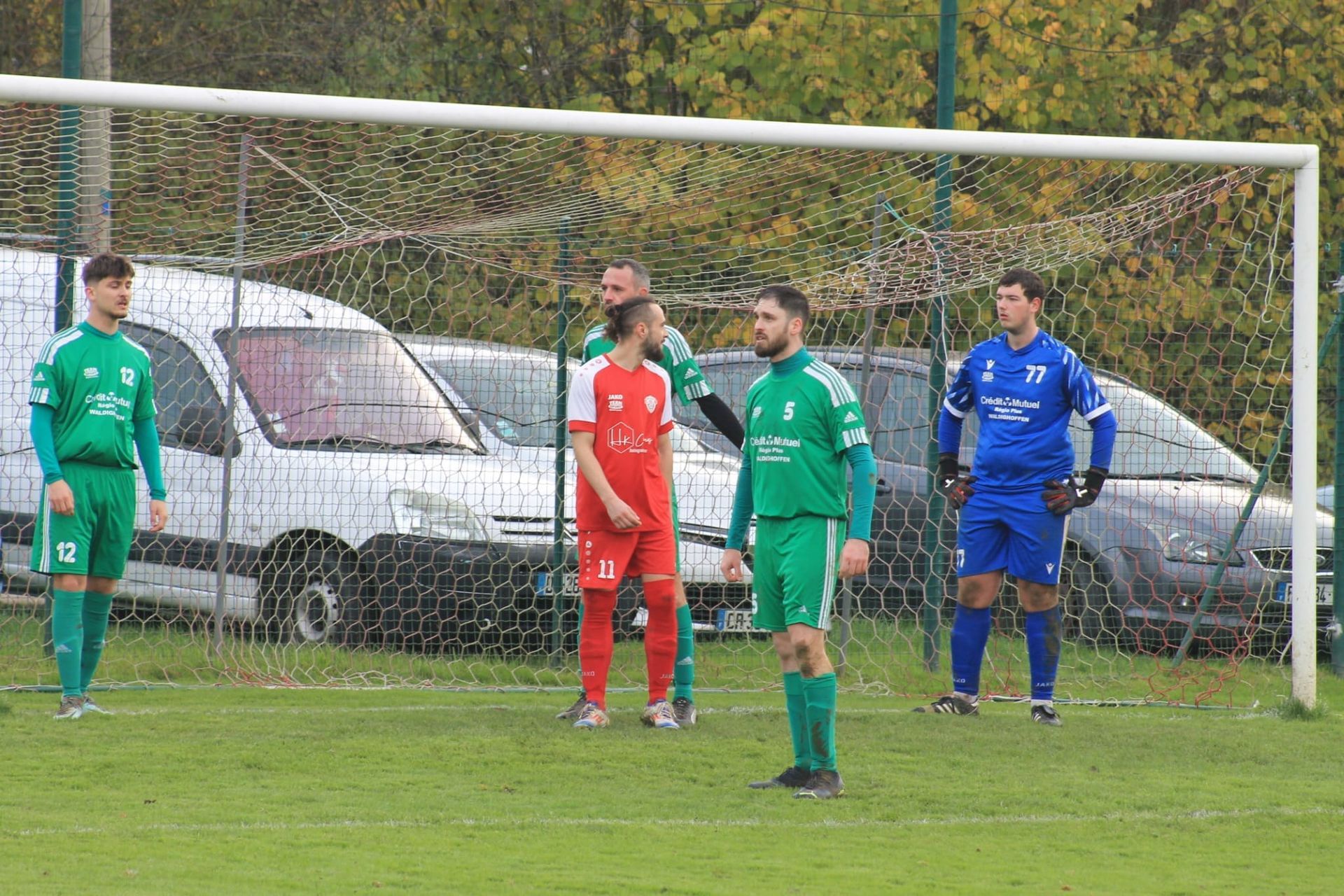 Un groupe de joueurs de football se tient sur un terrain devant un but.