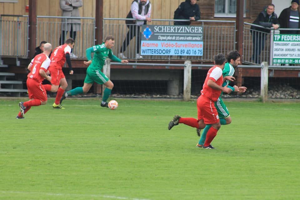 Un groupe de joueurs de football jouent à un jeu sur un terrain.