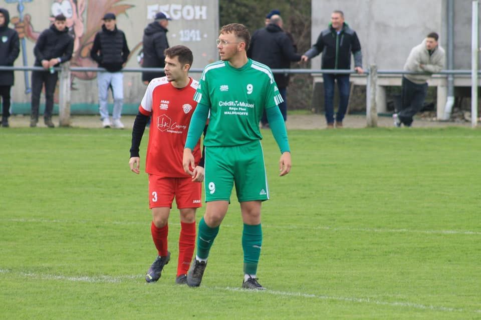 Deux joueurs de football marchent sur le terrain pendant un match.