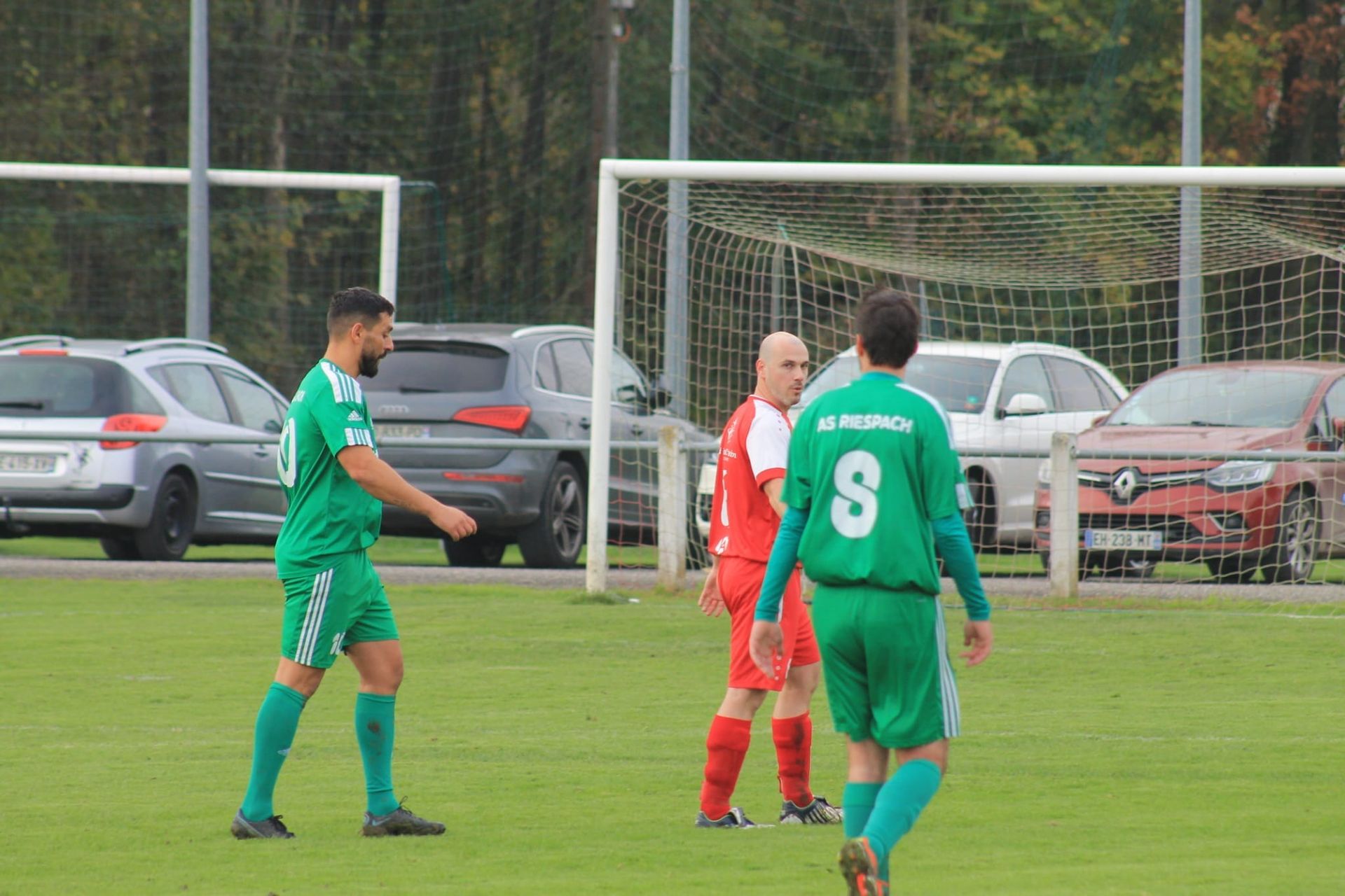 Un groupe de joueurs de football se tient sur un terrain devant un but.