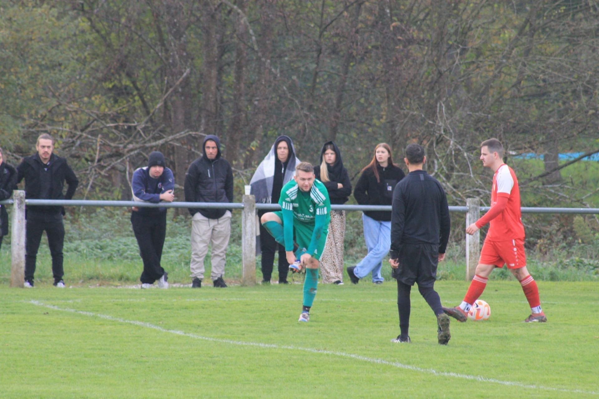 Un groupe de personnes regarde un match de football sur un terrain.