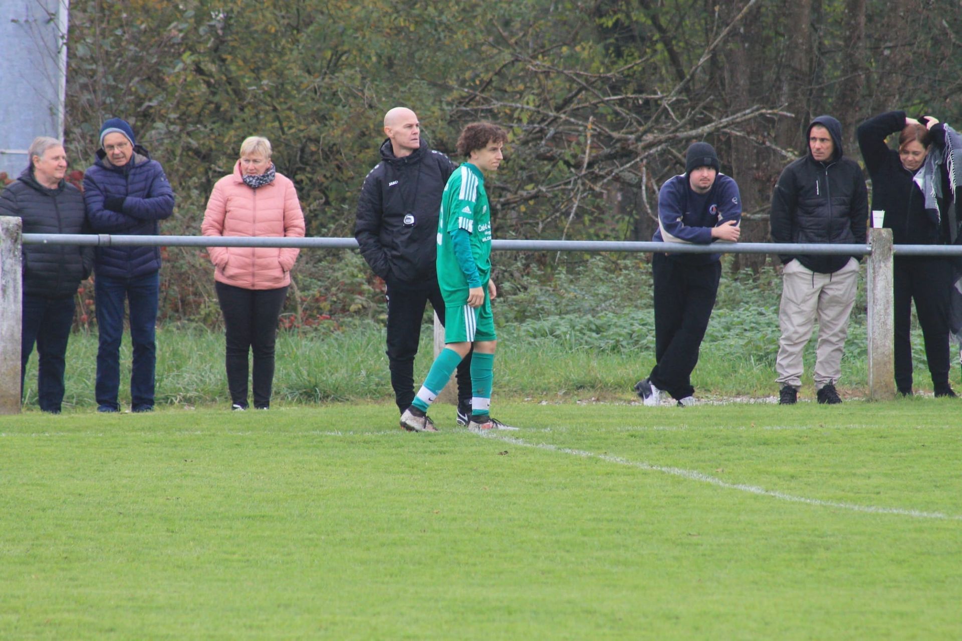 Un groupe de personnes regarde un match de football sur un terrain.