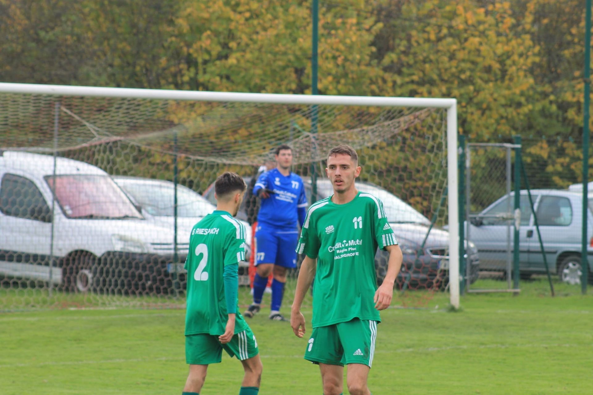 Un groupe de joueurs de football se tient sur un terrain devant un but.