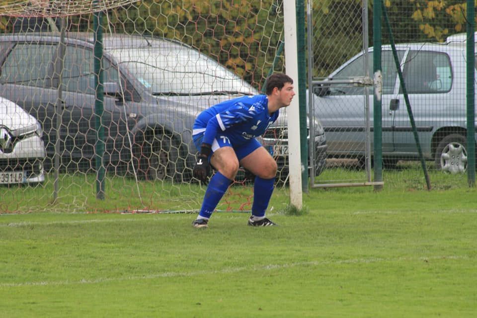 Un joueur de football se tient devant un but sur un terrain.