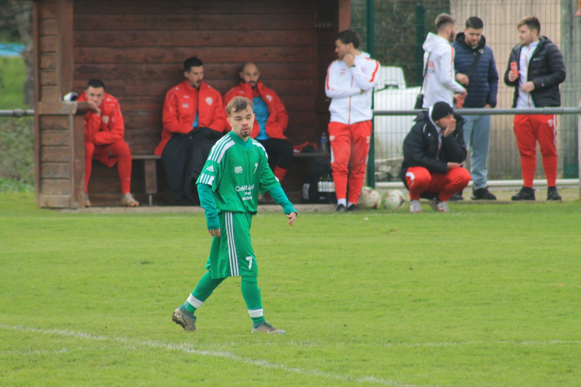 Un groupe d'hommes sont assis sur un banc sur un terrain de football.