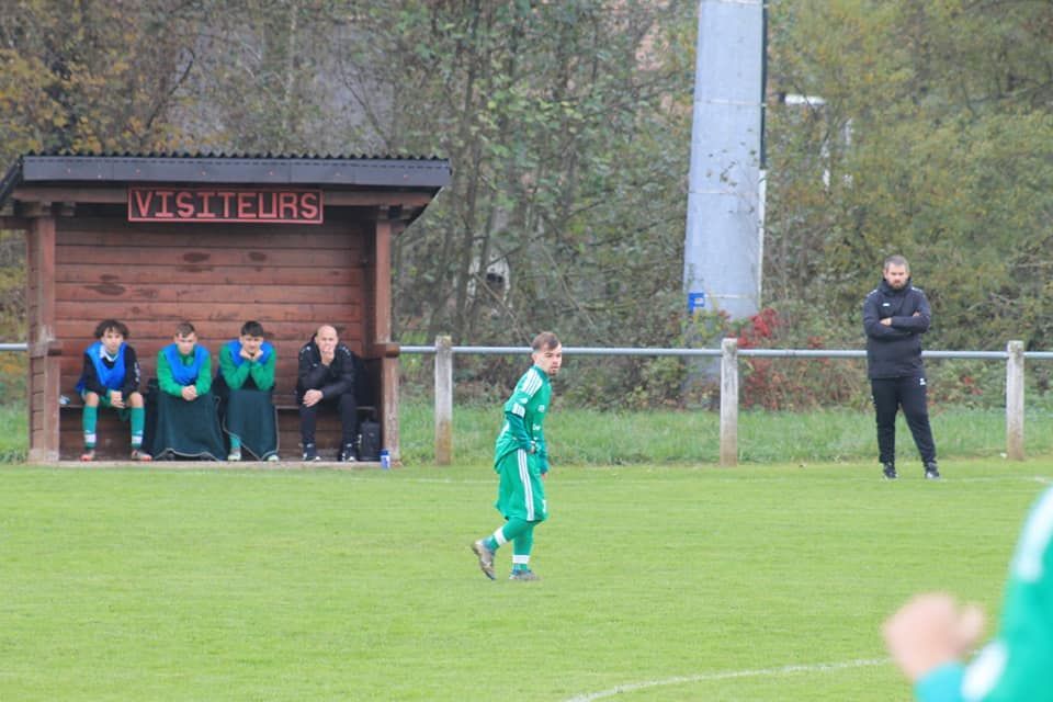 Un groupe de personnes sont assises dans un abri en bois sur un terrain de football.