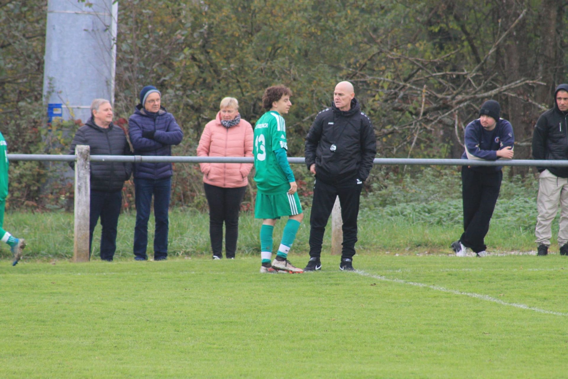 Un groupe de personnes se tient sur un terrain de football et regarde un match.