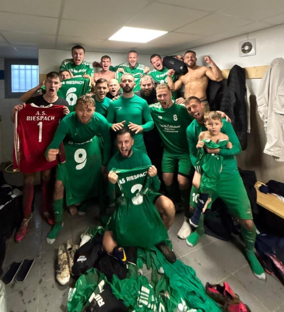 Une équipe de football pose pour une photo sur un terrain.