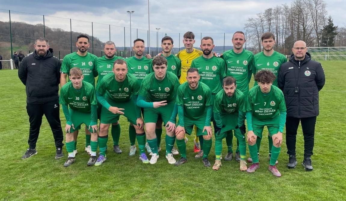 Une équipe de football pose pour une photo sur un terrain.