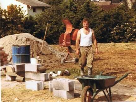 Un homme se tient debout à côté d'une brouette sur un chantier de construction.