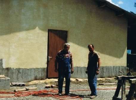 Deux hommes se tiennent devant un bâtiment et se parlent.