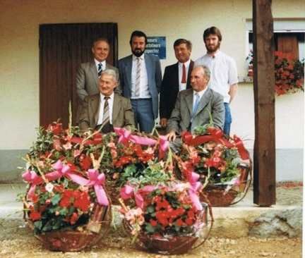 Un groupe d'hommes pose avec des paniers de fleurs devant un bâtiment