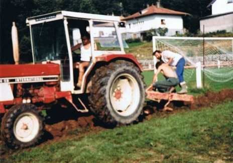 Un homme se tient debout à côté d'un tracteur dans un champ.